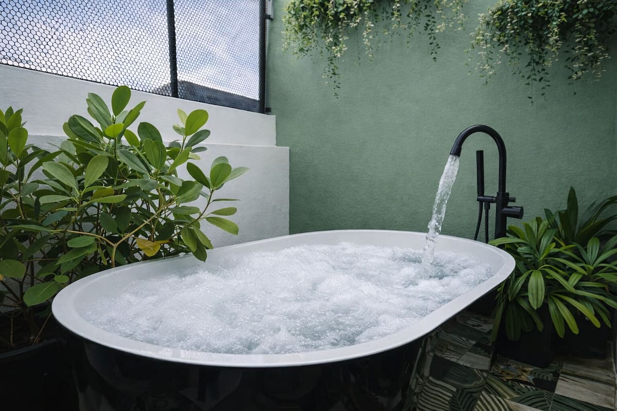 Un jacuzzi con agua corriendo, rodeado de plantas y un muro verde.