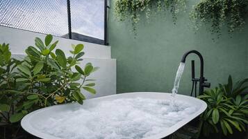 Un jacuzzi con agua corriendo, rodeado de plantas y un muro verde.