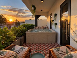 Une terrasse sur le toit dotée d’un jacuzzi, d’un espace salon et de plantes en pot.