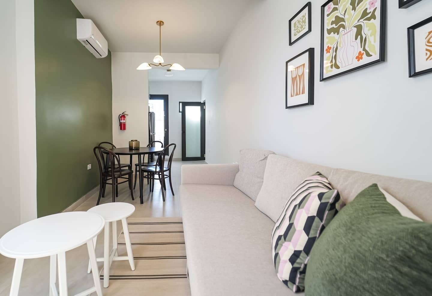 Een moderne woonkamer met een bank, een eettafel met stoelen en een trap naar een andere kamer.