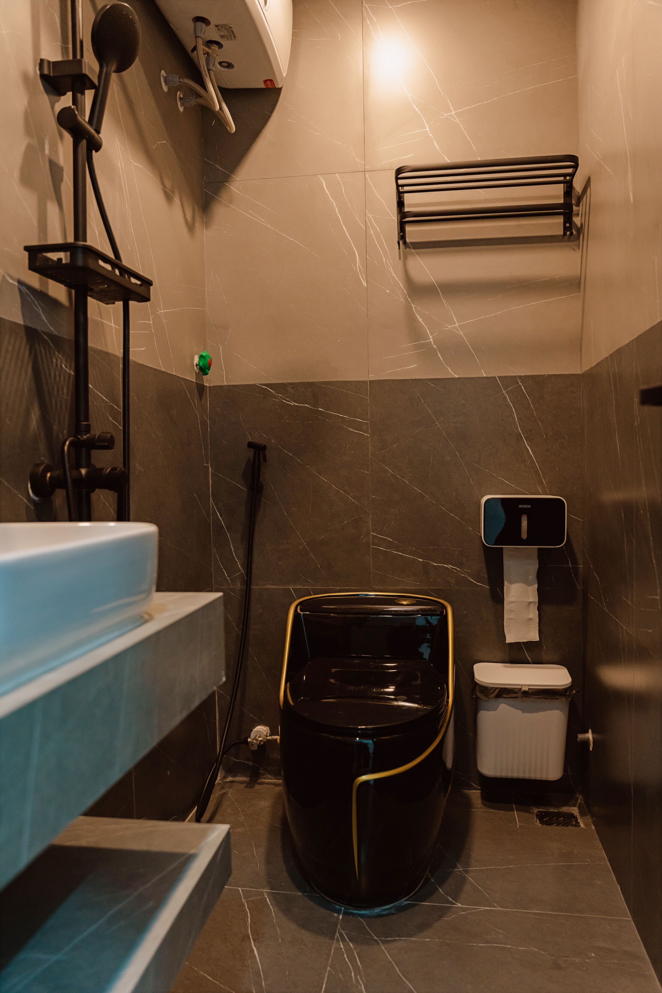 Ein modernes Badezimmer mit Toilette in Schwarz, einem Waschbecken und einer Duschkabine.