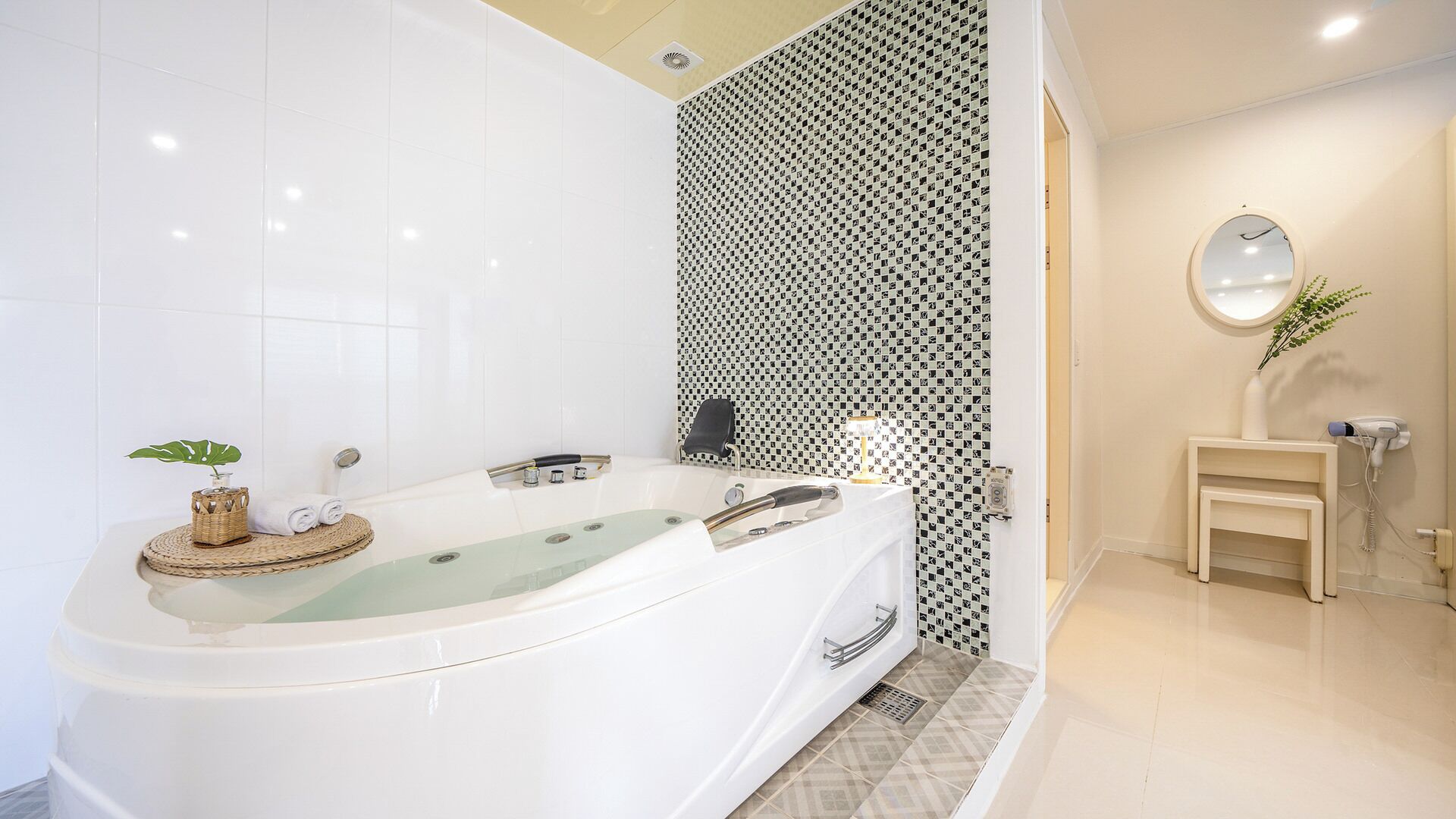 Une salle de bain moderne avec une baignoire sur pieds, une petite table de chevet et un miroir fixé au mur.