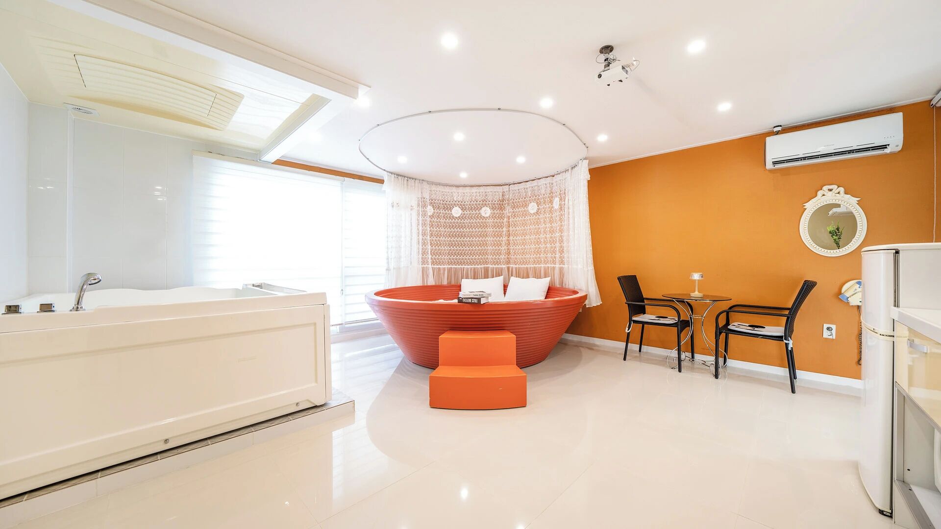 A modern bathroom with a bathtub, a red circular seating area, and a small table with chairs.