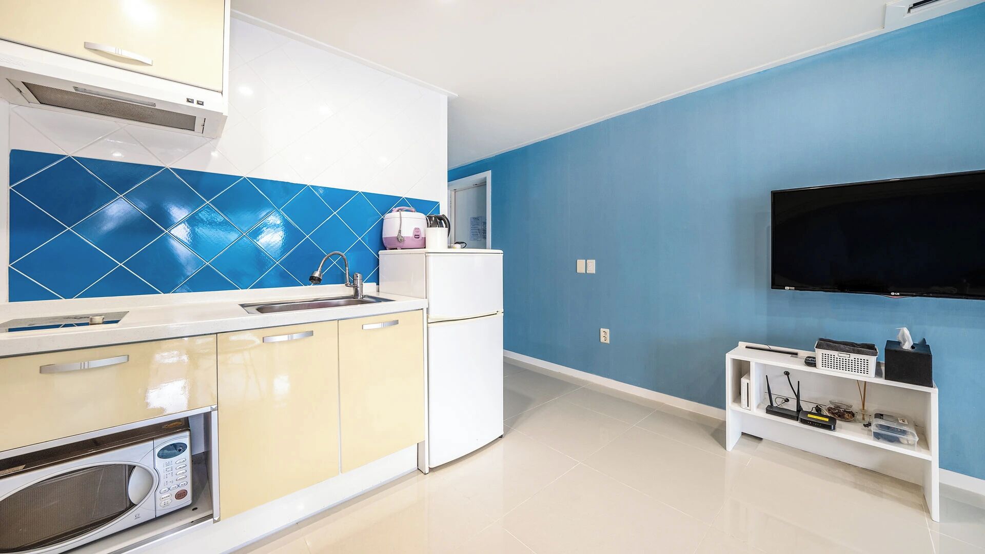 A modern kitchen with a microwave, sink, and a blue tiled backsplash.