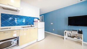 Una cocina moderna con microondas, pileta y un salpicadero de azulejos azules.