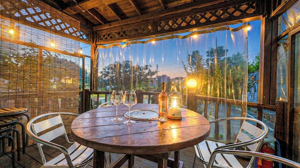 An outdoor dining area with a round table, chairs, a bottle, and a lantern.
