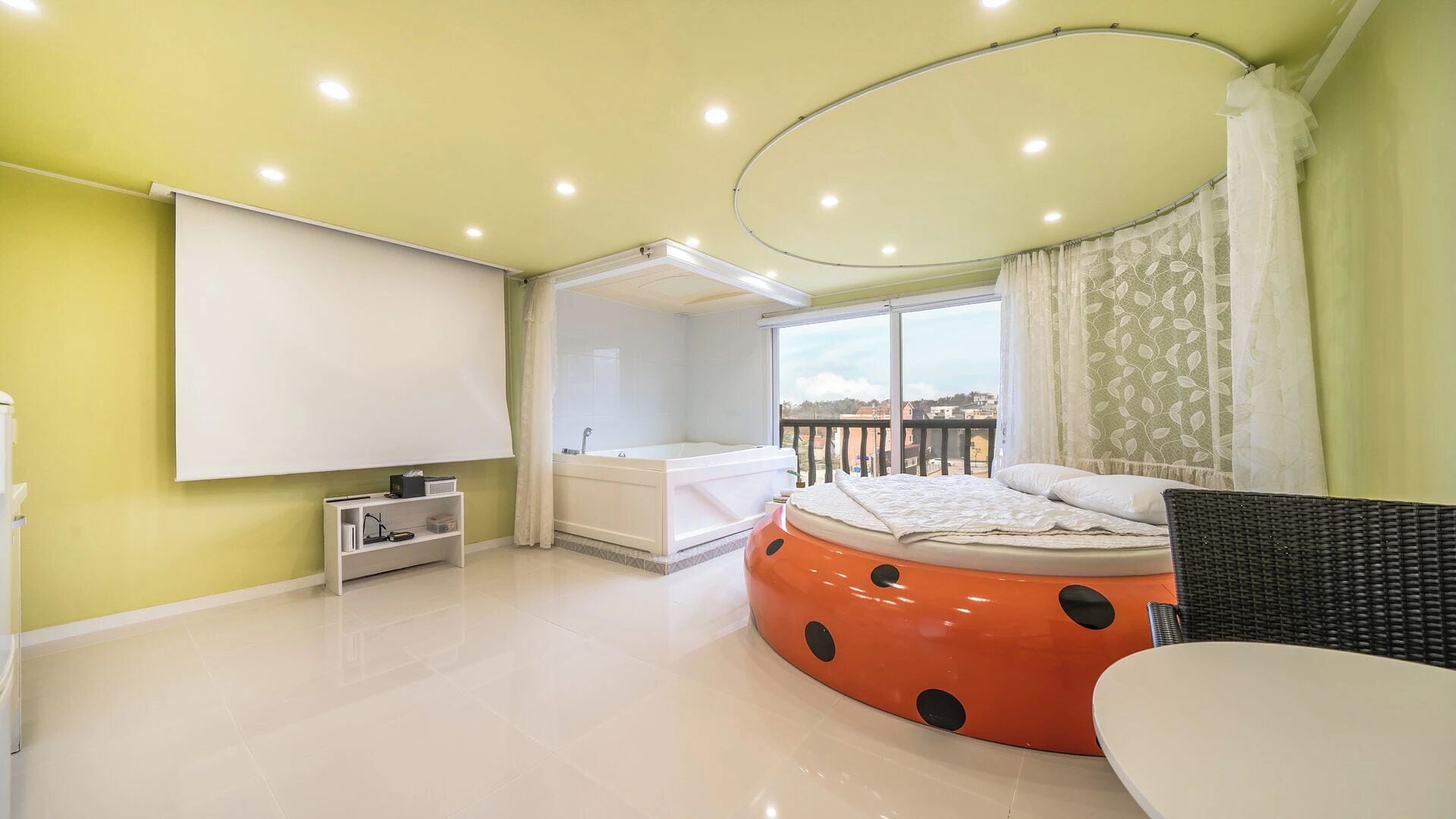 Una camera da letto con un letto grande, una vasca da bagno, un balcone con vista e un televisore a parete.