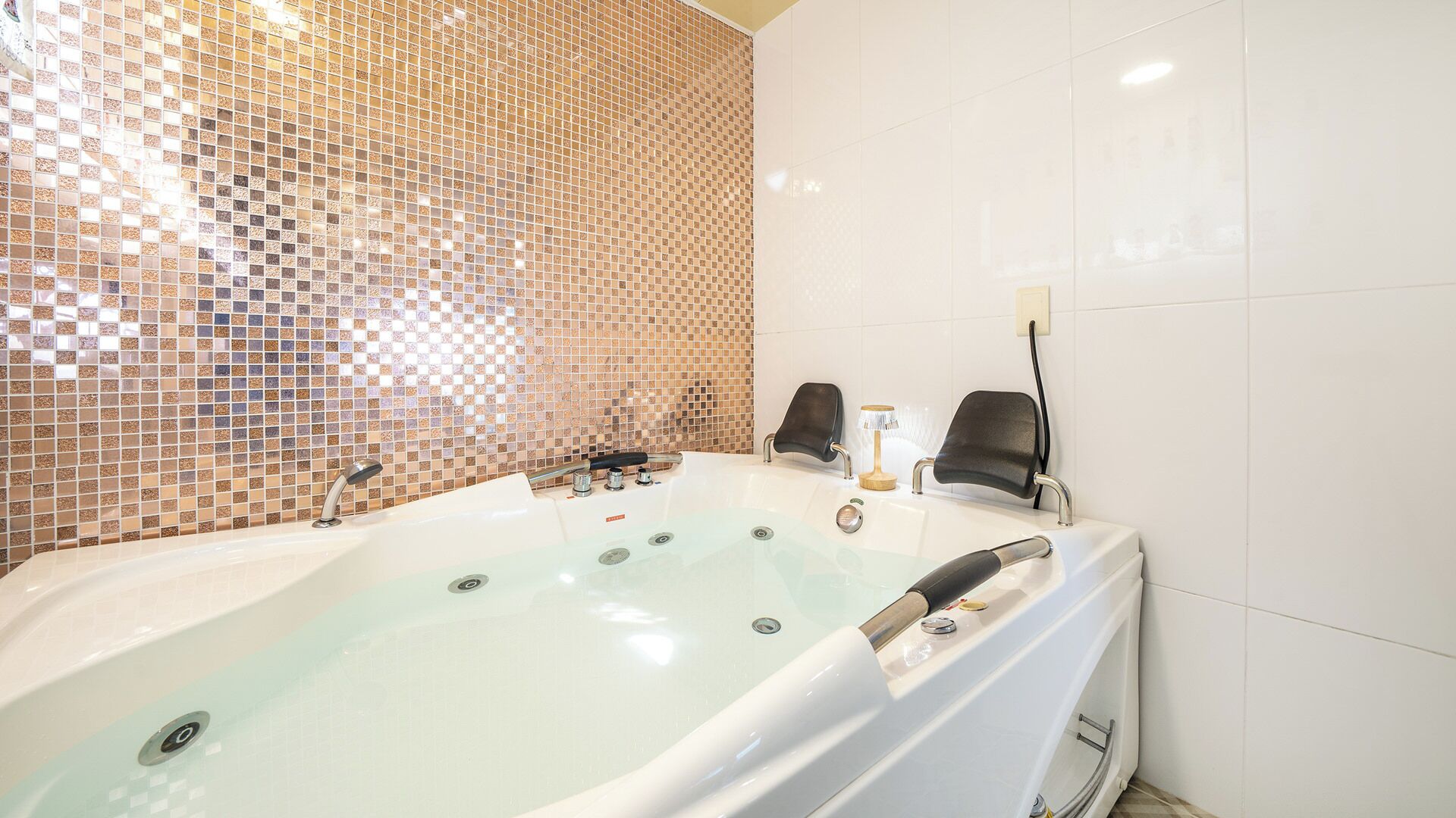 Une salle de bain avec une grande baignoire, une douche et un mur carrelé.