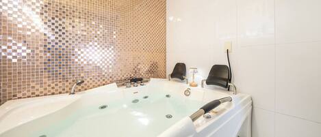 Une salle de bain avec une grande baignoire, une douche et un mur carrelé.