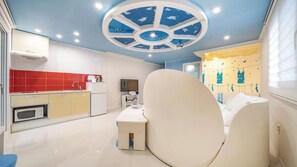 A modern kitchen with a central island, a dining area with a white chair, and a ceiling with a circular design. - Gyeongju Nunkoip Pension (Gyeongju)