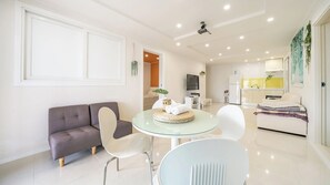 A modern living room with a sofa, a glass dining table, and a kitchen area in the background. - Gyeongju Nunkoip Pension (Gyeongju)