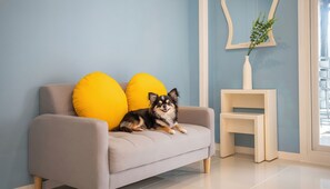 A light-colored sofa with two yellow pillows, a small white side table, and a mirror on the wall. - Gyeongju Nunkoip Pension (Gyeongju)