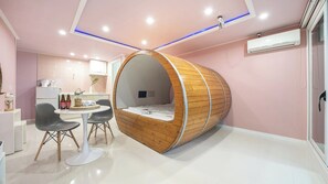 A modern interior with a unique curved sleeping pod, a dining area with a white table and chairs, and a kitchenette. - Gyeongju Nunkoip Pension (Gyeongju)