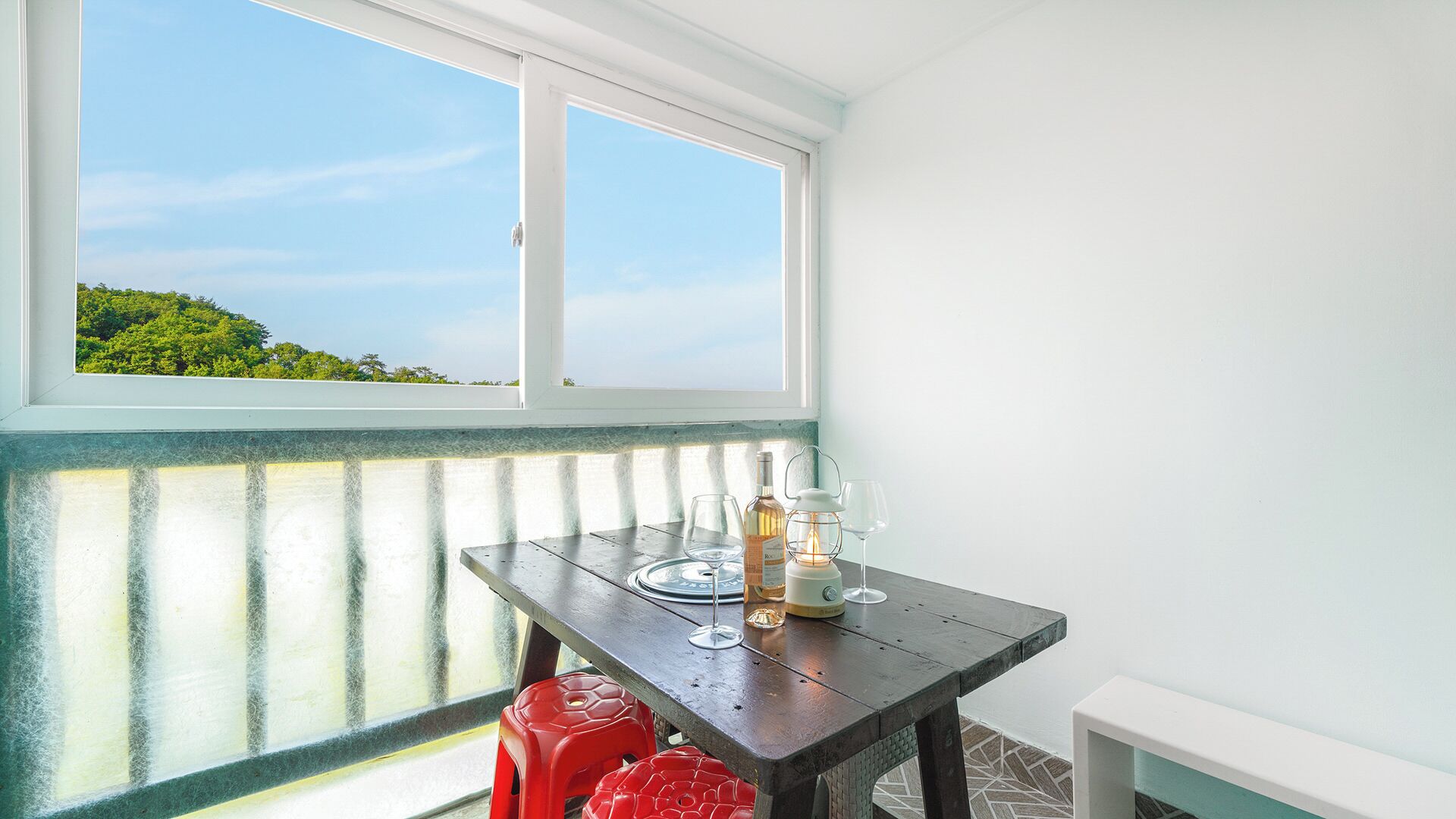 A room with a table, two chairs, a bottle, and two glasses.