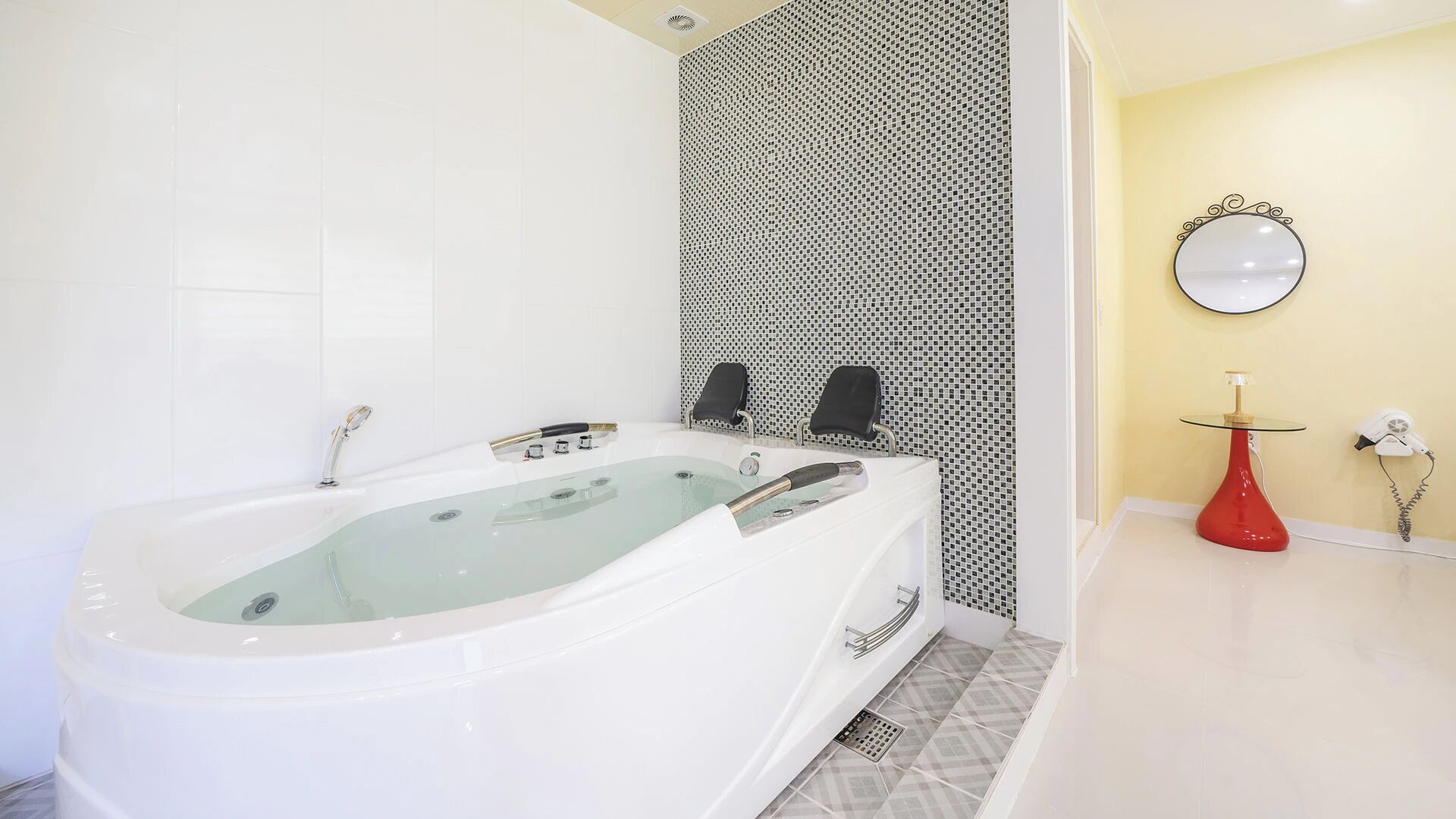 Ein modernes Badezimmer mit einer freistehenden Badewanne, einer Duschkabine und einem Waschtisch mit einer roten Vase.