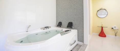Ein modernes Badezimmer mit einer freistehenden Badewanne, einer Duschkabine und einem Waschtisch mit einer roten Vase.