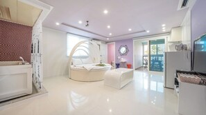 Un dormitorio moderno con una cama curvada, un tocador y un amplio ventanal.