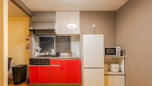 Una cocina compacta con gabinetes rojos, un refrigerador blanco, un microondas y una estufa a gas.