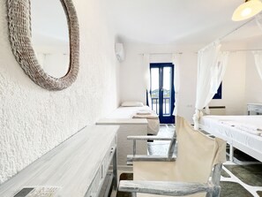 Een kamer met een bed, een stoel, een bureau, een spiegel en een raam met gordijnen.