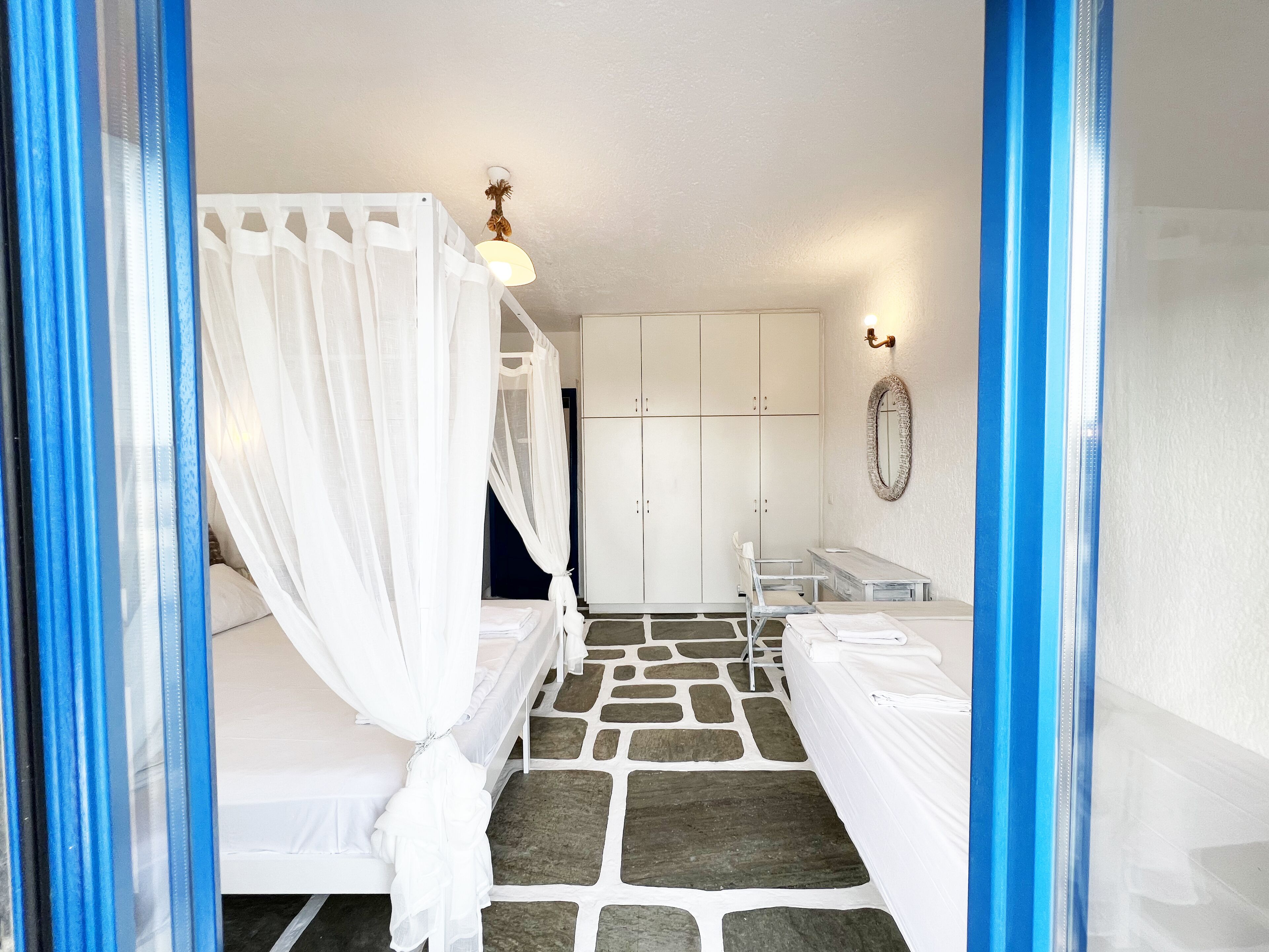 A bedroom with a canopy bed, a wardrobe, a mirror, and a small table.