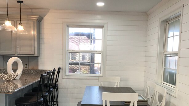 Eine Küche mit Essbereich, ausgestattet mit einem Holztisch und Stühlen, einem Fenster und Pendelleuchten.