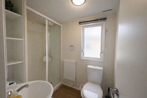 A bathroom with a bathtub, toilet, and a glass-enclosed shower.