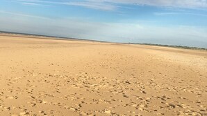 A vast sandy beach with footprints, a clear sky, and distant vegetation. - The Lakes Escape Haven Golden Sands Mablethorpe (Mablethorpe)