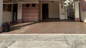 Una casa de dos pisos con un porche cubierto, entrada protegida por un portón y un camino de entrada empedrado.