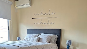 Un dormitorio con cama, mesita de noche, lámpara y aire acondicionado.