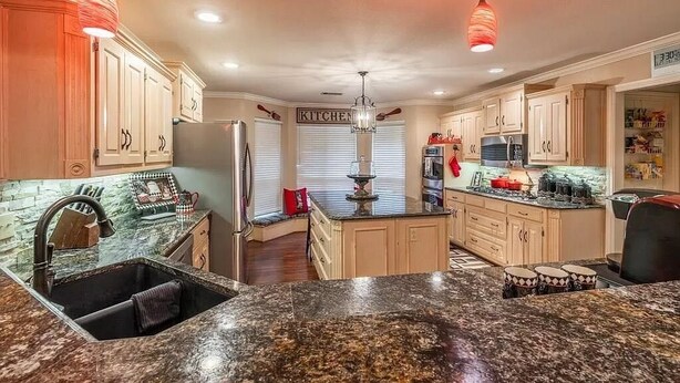 A kitchen with granite countertops, wooden cabinets, and a central island. - Spacious 7-bedroom, 15-acre estate with private 2-boat and fishing dock! (Alba)