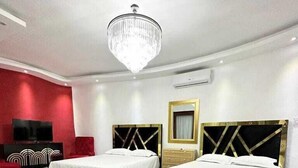 Habitación de hotel con dos camas, un televisor, una pared decorada en rojo y un candelabro.