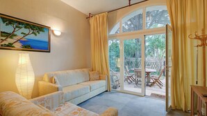 A cozy living room with a sofa, a lamp, and a painting of a tree. - Villa Azzurra Front Beach - Pool, Gassin, France (Gassin)