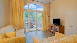 A living room with a sofa, a television, and a sliding glass door leading to an outdoor patio. - Villa Azzurra Front Beach - Pool, Gassin, France (Gassin)
