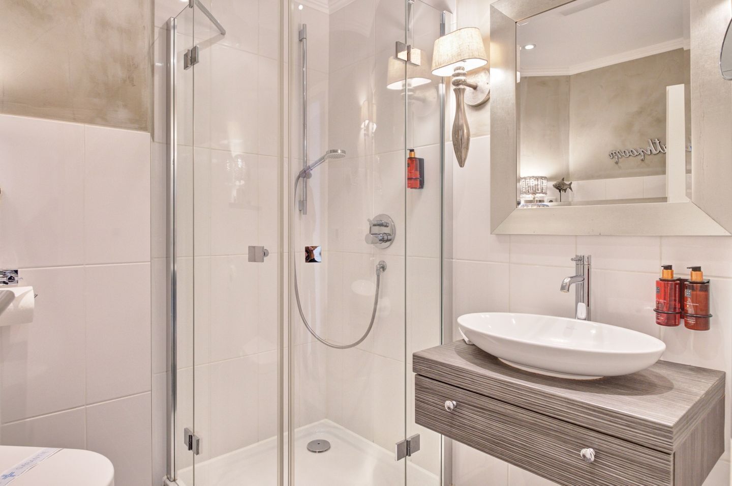 A modern bathroom with a glass shower enclosure, a white sink, and a wooden vanity.