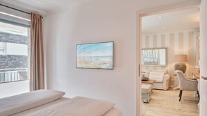 Een hotelkamer met een bed, een schilderij van een strand, uitzicht op de stad, een bank en een stoel.