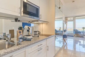 A modern kitchen with a built-in microwave, coffee machine, and a robotic vacuum cleaner.