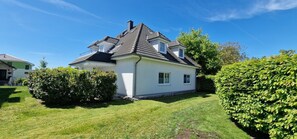 Una casa a due piani con tetto spiovente, un piccolo garage annesso e un prato curato.