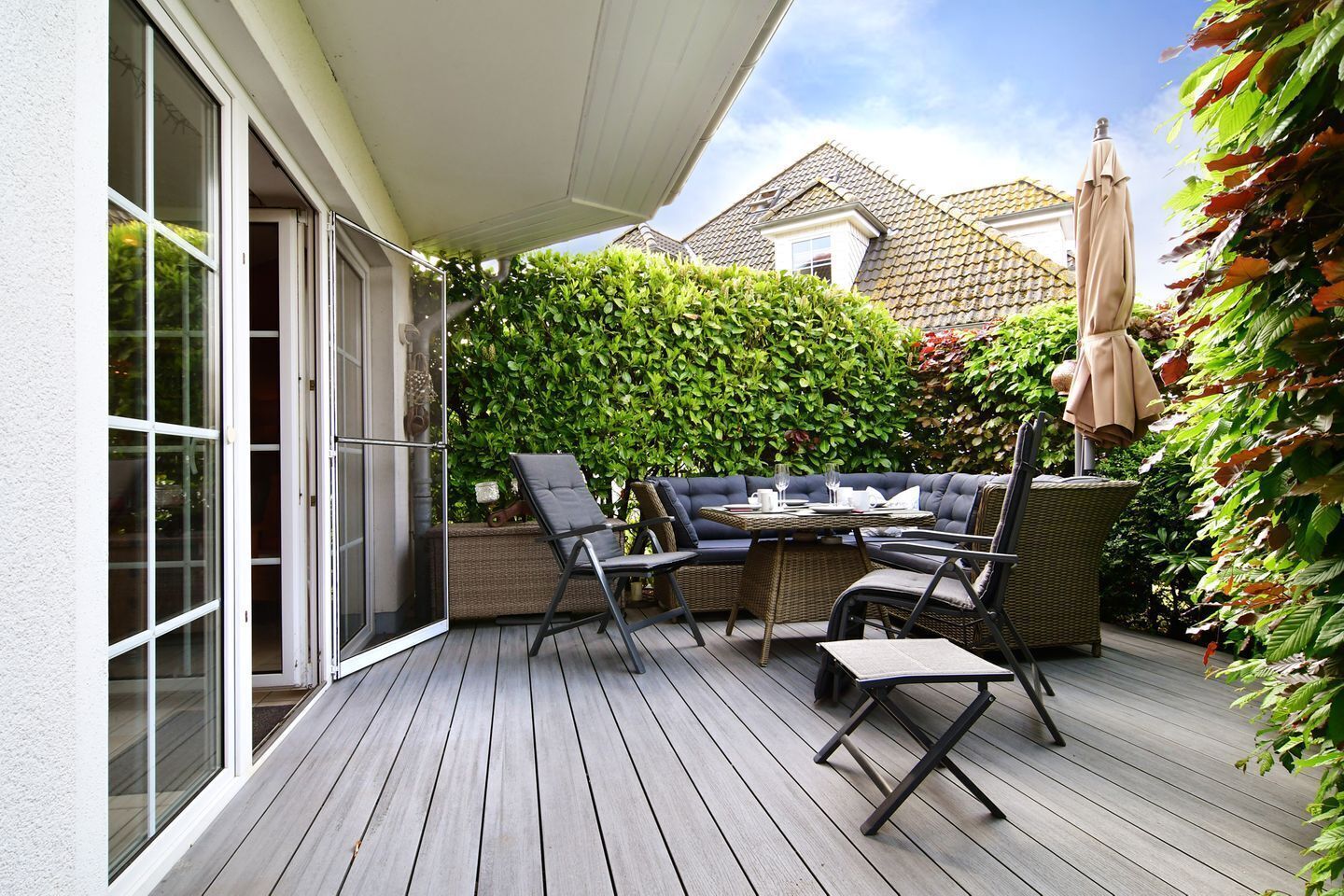An outdoor patio with a dining table, chairs, and a covered seating area.