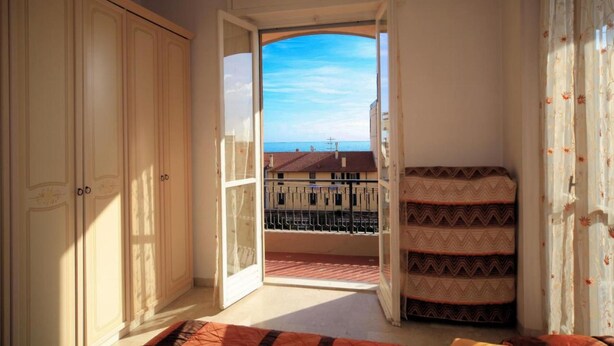 A room with a balcony, a large wardrobe, and a patterned sofa. - Vittorio Veneto 9 Int 20 (Borghetto Santo Spirito)