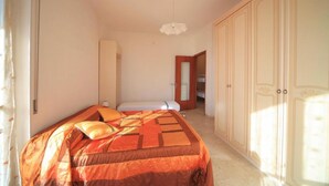 A bedroom with a bed, a wardrobe, and a door leading to another room. - Vittorio Veneto 9 Int 20 (Borghetto Santo Spirito)