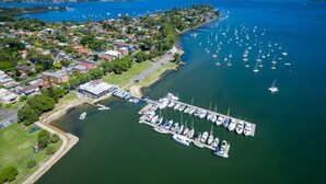 An aerial view of a marina with numerous boats docked, surrounded by residential buildings and greenery. - Sailors Cove | Pet Friendly (Point Frederick)
