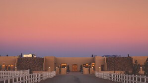 A hotel entrance with a central door, white picket fence, and a stone wall. - Tirrito Farm (Willcox)