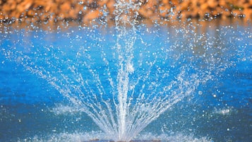 A water fountain with a clear blue sky and a rocky background.