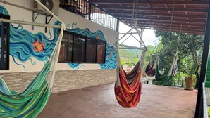A covered outdoor area with a hammock, a mural, and a view of greenery. - Beautiful Carillo poolside condo w/ AC! Location+ (Puerto Carrillo)