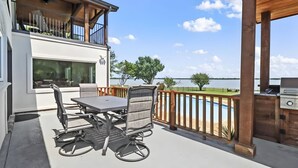 Une terrasse avec une table et des chaises, un barbecue et une vue sur un lac.
