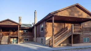 Un edificio de estilo cabaña de troncos con un porche cubierto, una escalera y una chimenea.