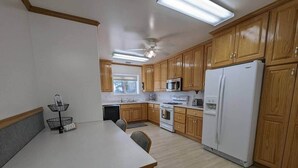 Una cocina compacta con armarios de madera, un refrigerador blanco, un microondas y una estufa.