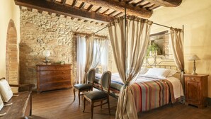 Une chambre à coucher rustique avec un mur en pierre, des meubles en bois et un lit à baldaquin.