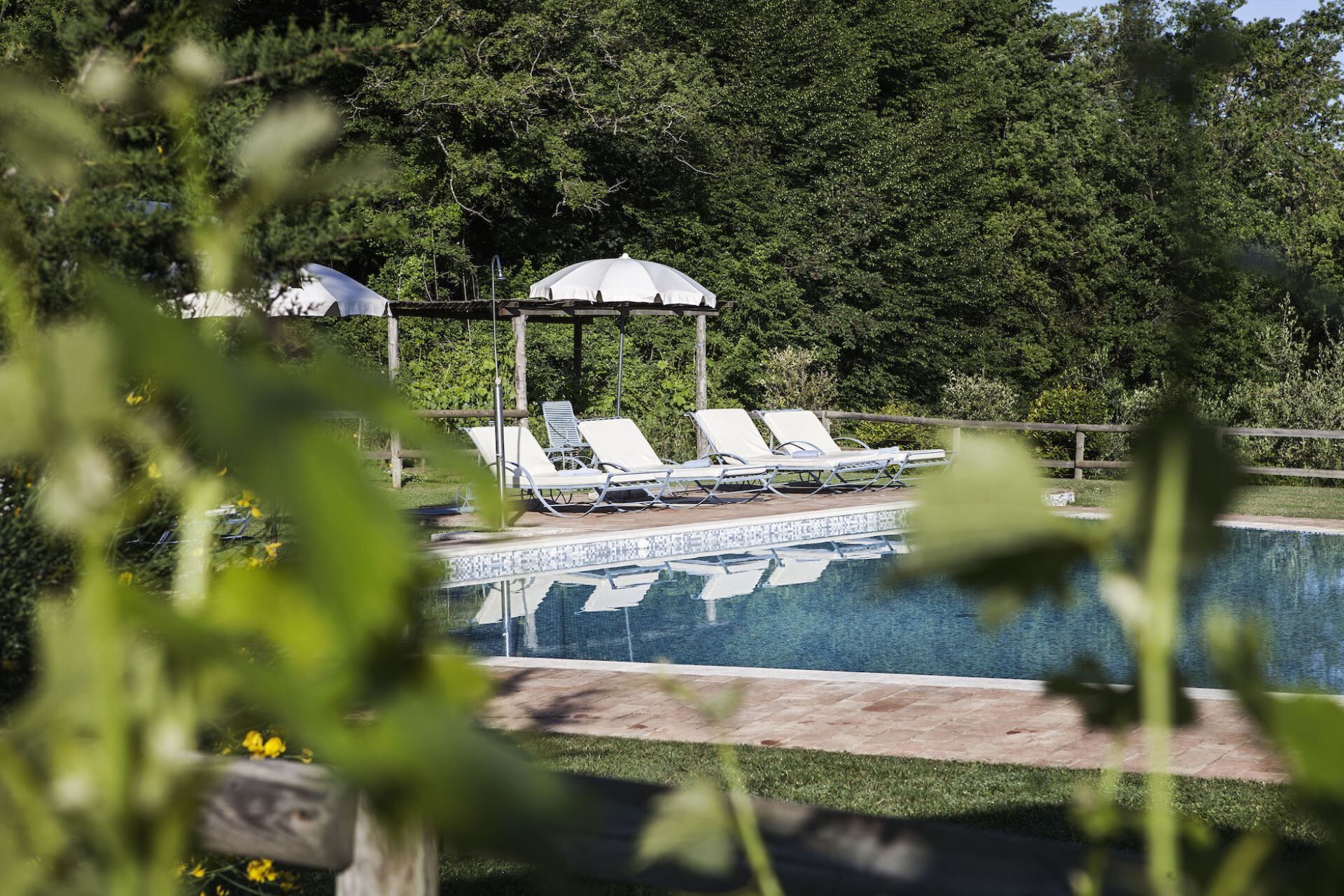 Area piscina con lettini e zona salotto coperta.