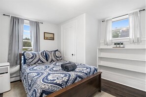 Cozy retreat with a large bed, bedside table, and window with white curtains.